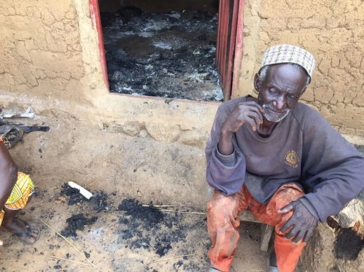 A man sits beside the remains of his burned out home in Kaduna. csi