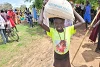A recipient of food aid holds aloft a sack of grain. csi