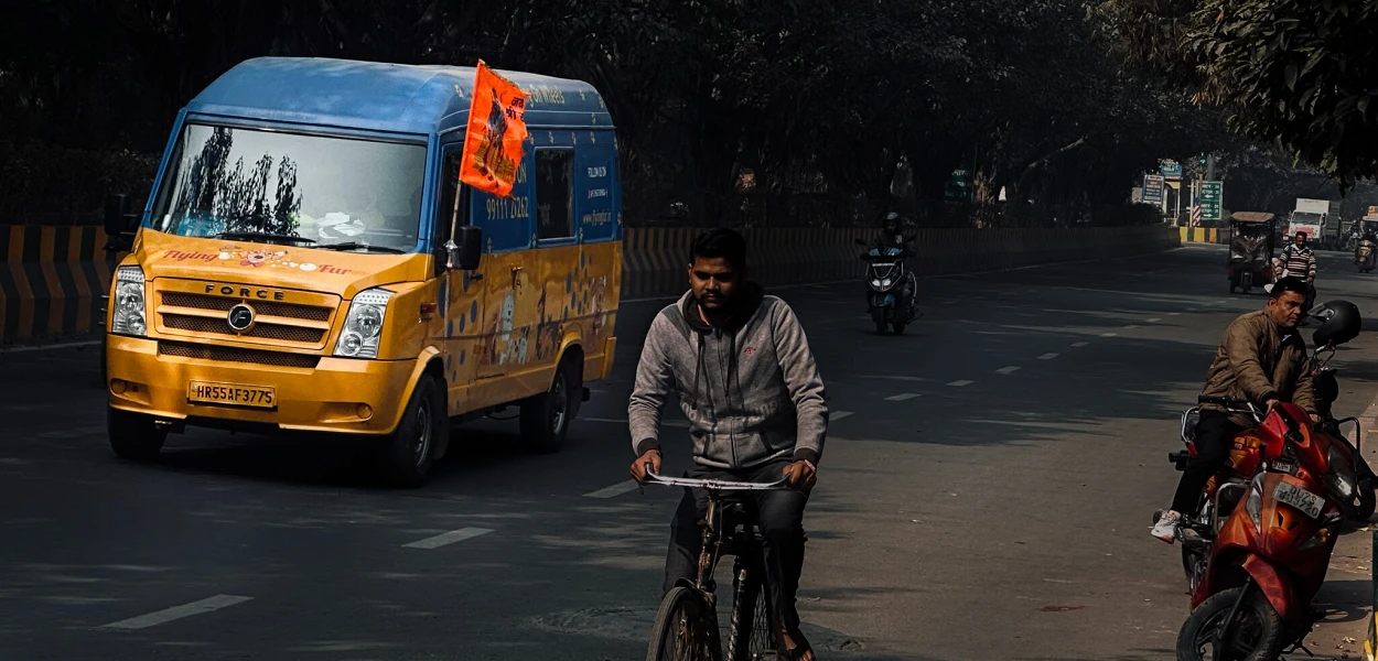 A cyclist rides past a van flying one of the ubiquitous saffron flags. csi